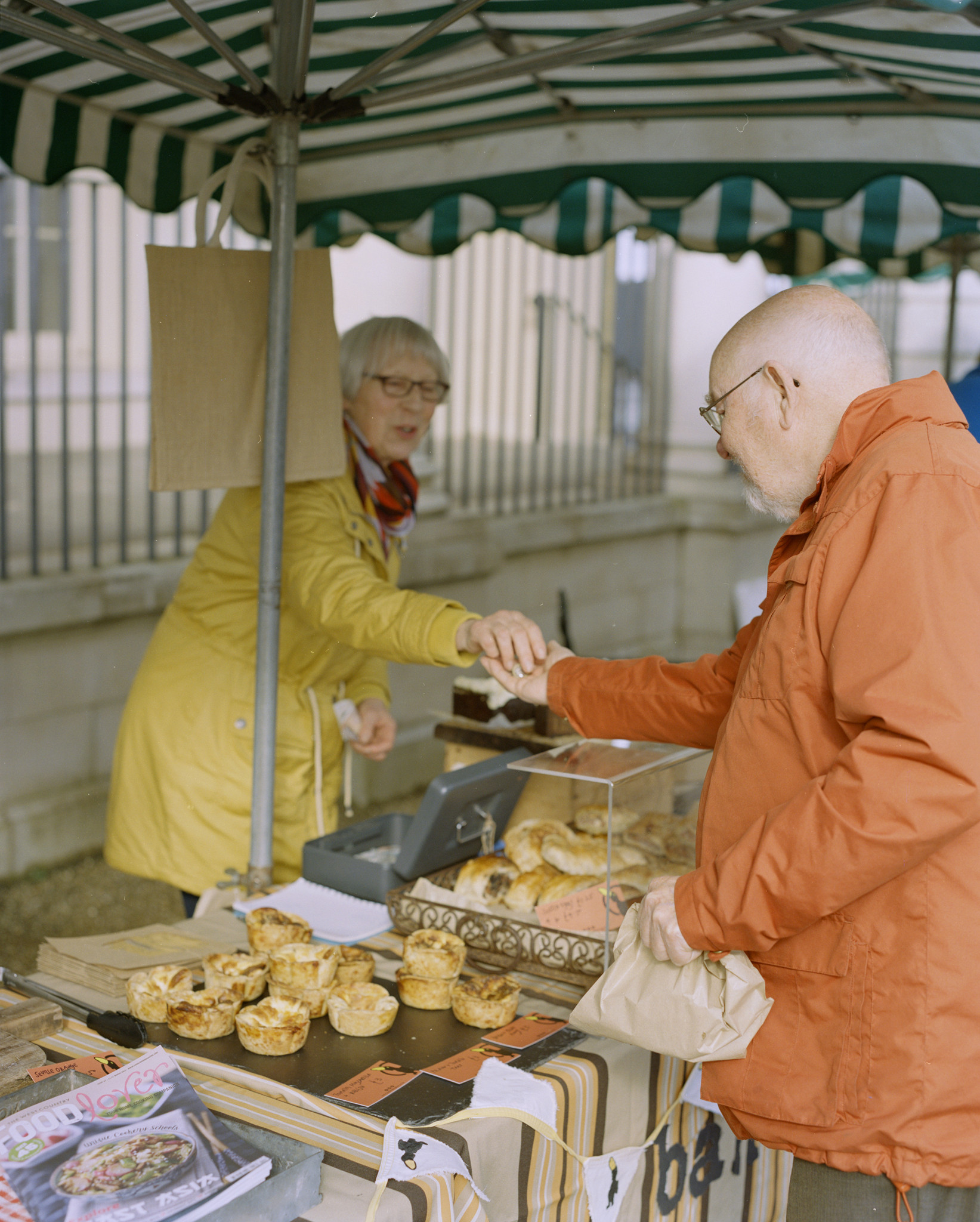 Image of man buying pastry from a woman in a market stall