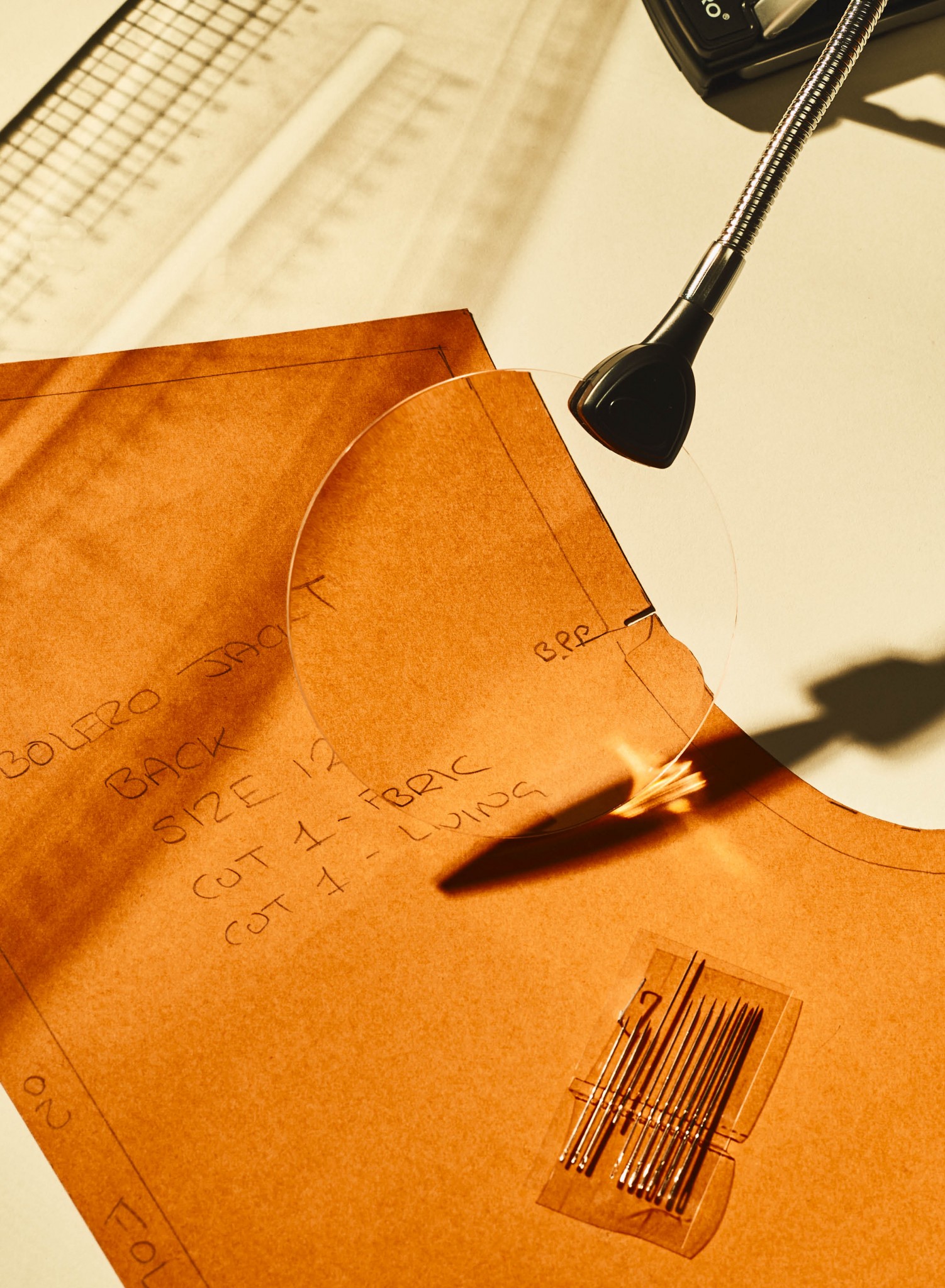 Closeup image of a pattern, sewing needles and rulers