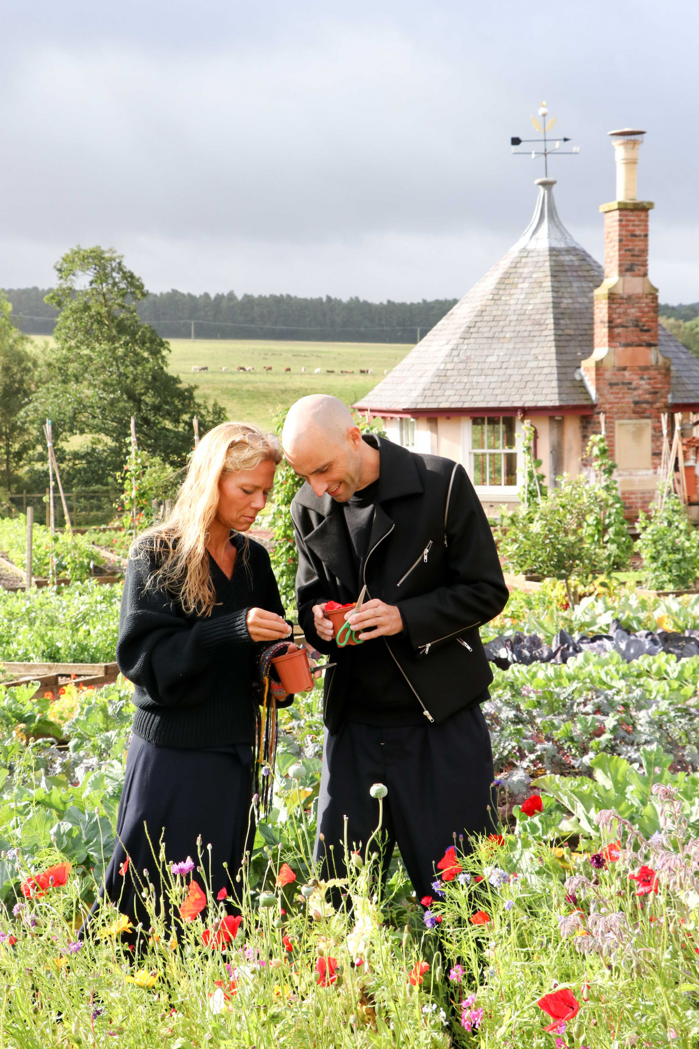 A man and a women standing in a garden looking at flowers